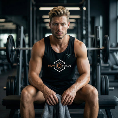 young athletic man sitting in gym wearing black Iron Focus tank top with geometric logo on chest holding towel after workout