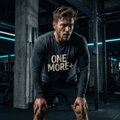 men’s dark grey One More Plus long sleeve performance gym shirt with motivational text design worn during intense workout in industrial gym