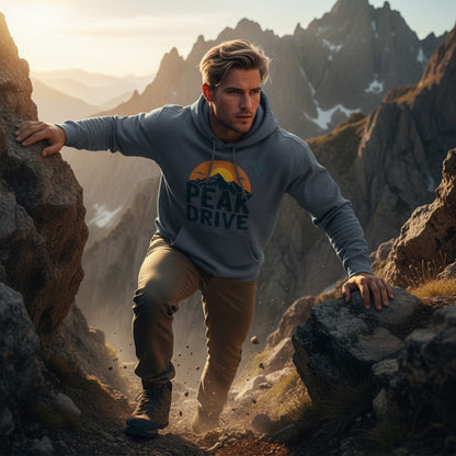man climbing rocky mountain trail at sunset wearing dark blue PEAK DRIVE hoodie, HorizonVibe men’s outdoor lifestyle image, strong action and adventure vibe