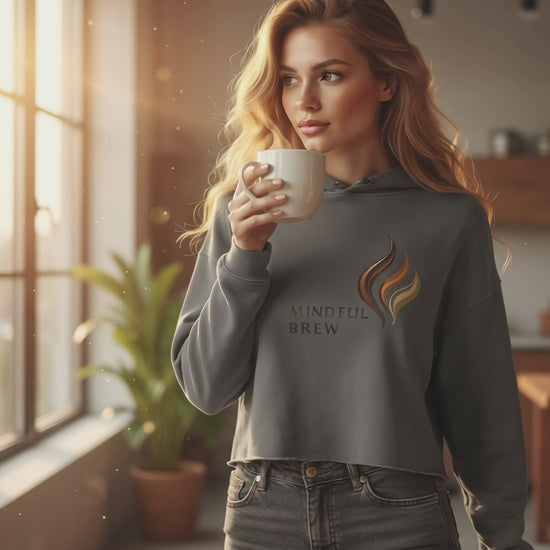 Woman model wearing HorizonVibe Mindful Brew storm gray cropped hoodie, sipping coffee in cozy morning sunlight, minimalist lifestyle
